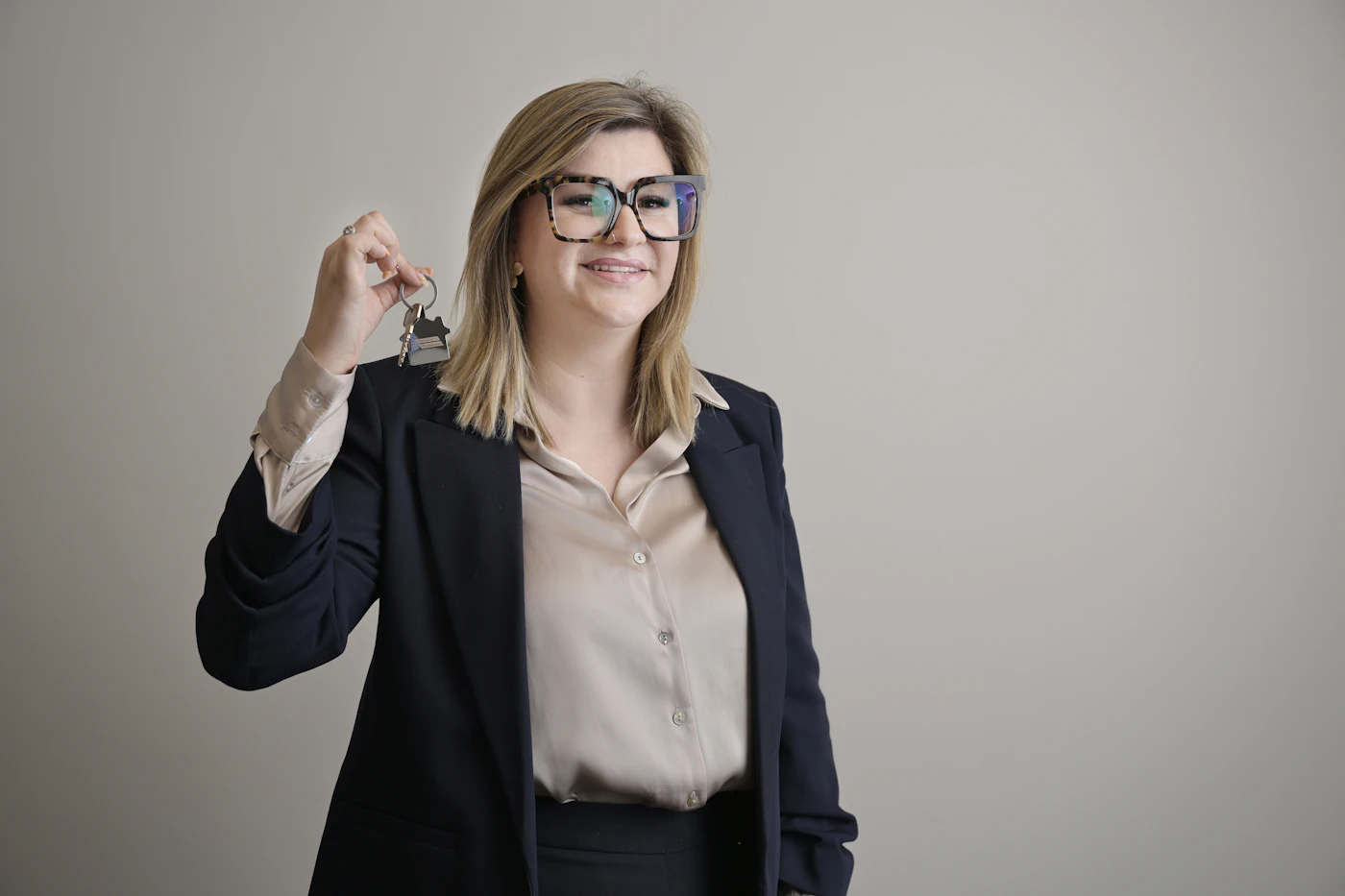 Smiling licensed real estate salesperson in Ontario holding house keys after passing the licensing exams